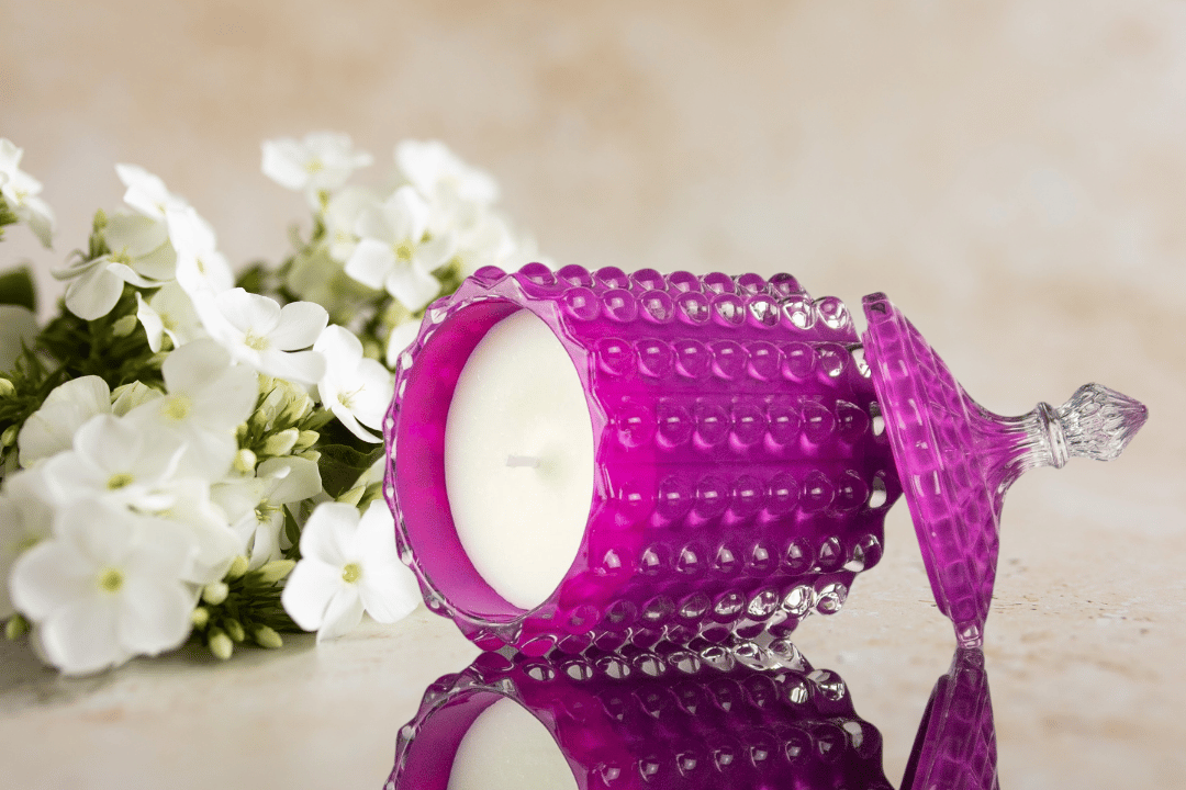 white floral scented candle in a purple glass container embossed with glass bubble and decorative lid