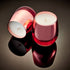 Two rose gold scented candles in an elegant glass design, one standing upright and the other lying down, with a reflective, shiny surface, filled with an aromatic smoky fragrance.